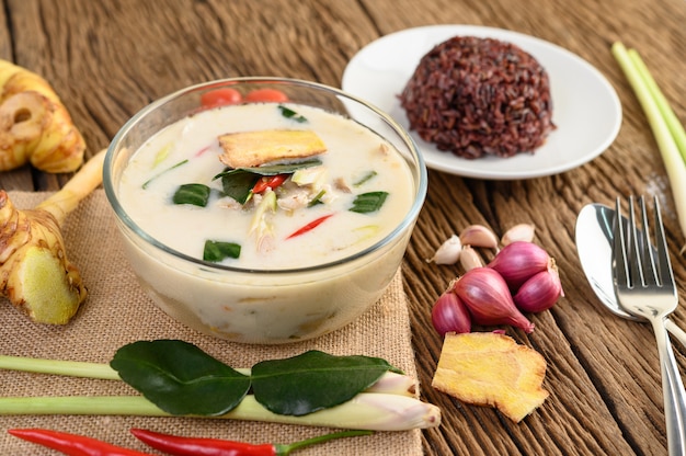 Tom Kha Kai w misce z liśćmi limonki kaffir, trawą cytrynową, czerwoną cebulą, galangą i chili.