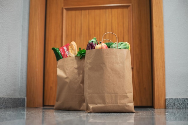 Torby na zakupy spożywcze stoją pod drzwiami domu lub mieszkania. dostawa warzyw i owoców podczas kwarantanny i samoizolacji.