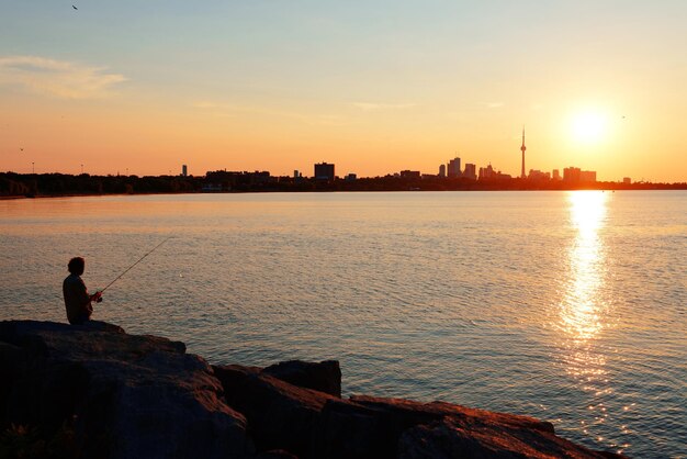 Toronto sunrise sylwetka nad jeziorem z połowów człowieka.