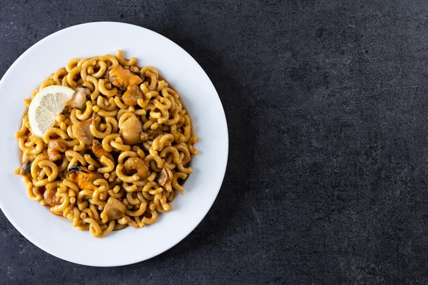 Tradycyjna hiszpańska fideua paella z makaronem na czarnym tle