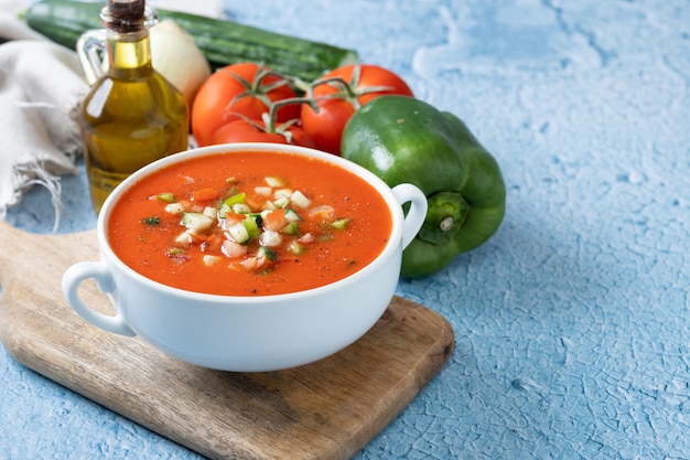 Tradycyjna hiszpańska zupa gazpacho w misce na niebieskim tle