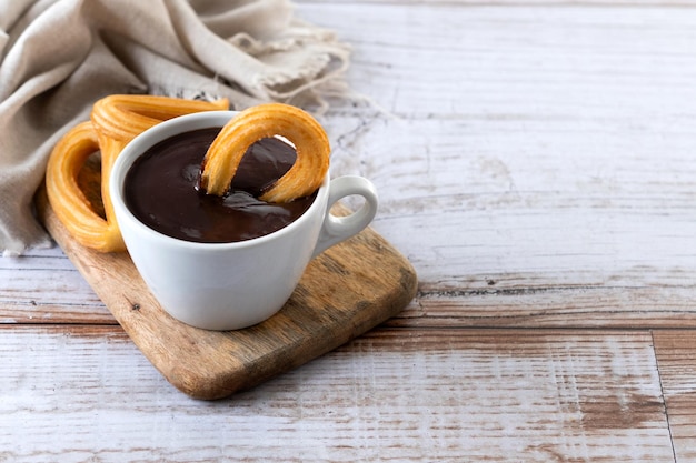 Bezpłatne zdjęcie tradycyjne hiszpańskie churros z gorącą czekoladą na drewnianym stole. skopiuj miejsce