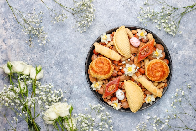 Bezpłatne zdjęcie tradycyjne święto azerbejdżanu ciasteczka novruz baklavas i shakarburas na czarnej płycie tacy na szarym tle betonu