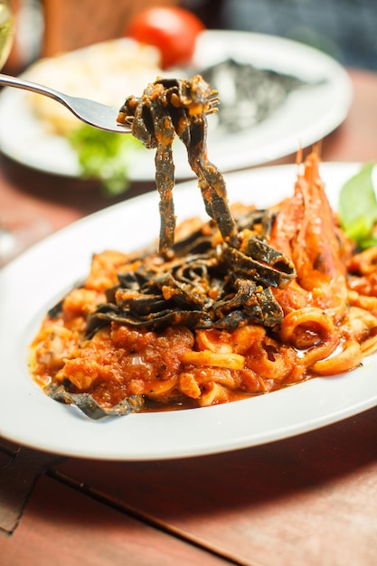 Bezpłatne zdjęcie tradycyjne włoskie danie czarne tagliatelle z owocami morza