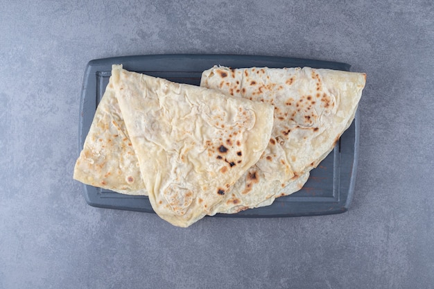 Bezpłatne zdjęcie tradycyjny chleb pszenny lavash na drewnianej tacy, na marmurze.