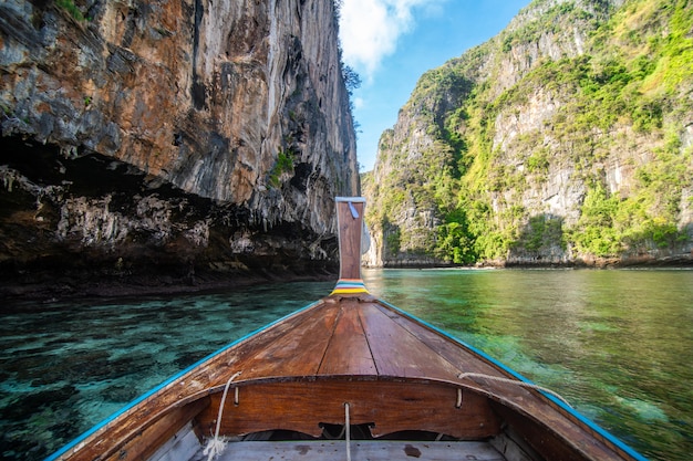 Tradycyjny drewniany longtail taksówki z ozdobnymi kwiatami i wstążkami na plaży Maya Bay na stromych wapiennych wzgórzach. Główny Tajlandia atrakci turystycznej tło, Ko Phi Phi Leh wyspa