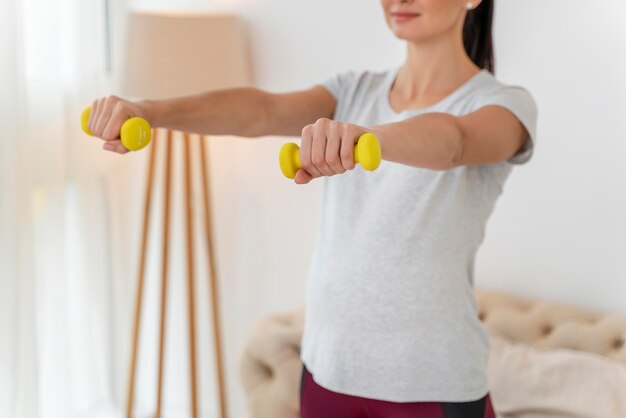 Trening kobiety w ciąży z żółtymi ciężarami