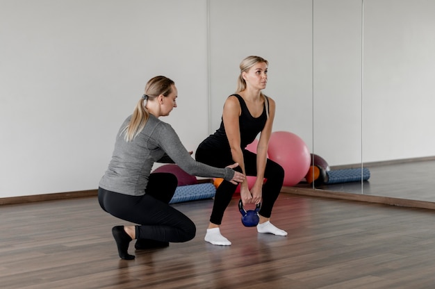 Trening z osobistym trenerem wykonującym przysiady