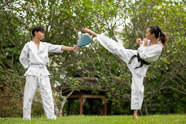 Bezpłatne zdjęcie treningi taekwondo odbywające się na świeżym powietrzu w naturze z dwiema osobami