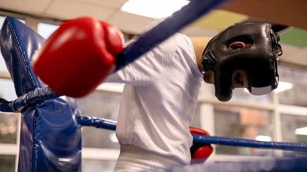 Trenujący bokser męski w kasku i rękawiczkach na ringu