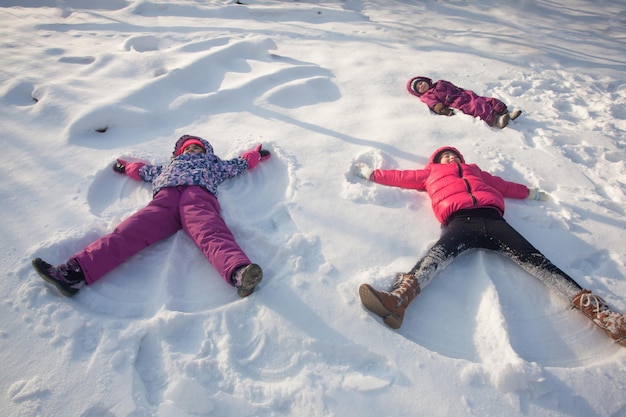 Troje Dzieci Robi śnieżne Anioły W Zimowy Słoneczny Dzień Premium Zdjęcia