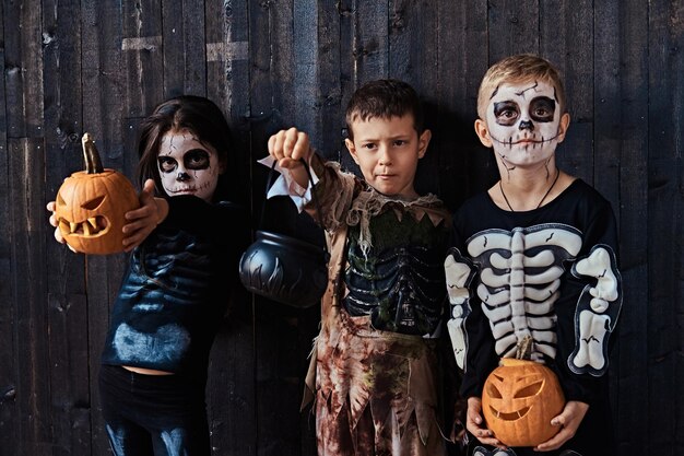 Troje uroczych dzieciaków w przerażających kostiumach podczas imprezy Halloween w starym domu. Koncepcja Halloween.