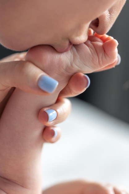 Bezpłatne zdjęcie troskliwa młoda matka całuje stopy dziecka z bliska