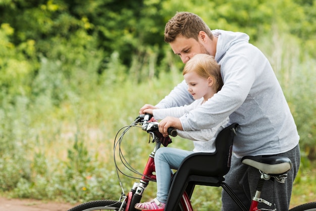 Troskliwy ojciec trzyma córkę na rowerze