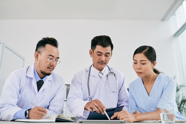 Trzech mężczyzn i kobiet lekarzy omawiających historię choroby pacjenta
