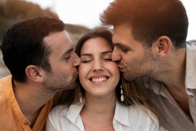 Trzech przyjaciół całuje się podczas wspólnego pozowania podczas imprezy na plaży