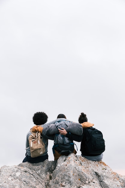 Trzech przyjaciół z ramionami siedzących na szczycie góry