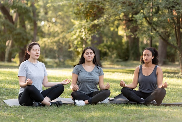 Trzy koleżanki robi joga w parku