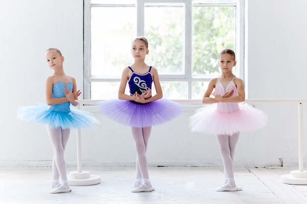 Bezpłatne zdjęcie trzy małe dziewczynki balet w tutu i pozowanie razem