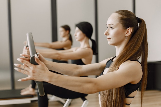 Trzy Młode Kobiety Sprawny Trening W Siłowni. Kobiety Noszące Czarne Ubrania Sportowe. Kaukaskie Dziewczyny ćwiczące Ze Sprzętem.