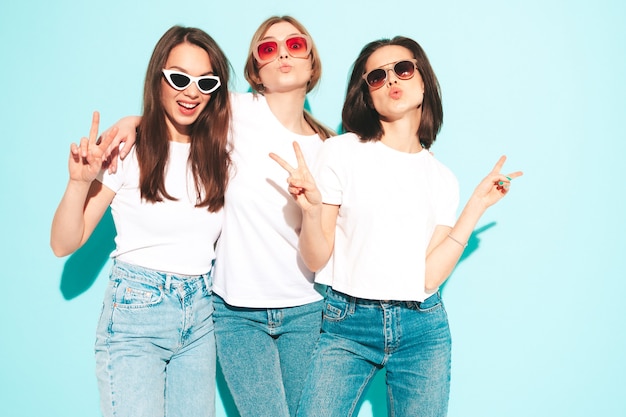 Trzy młode piękne uśmiechnięte kobiety hipster w modnej, tej samej letniej białej koszulce i dżinsach