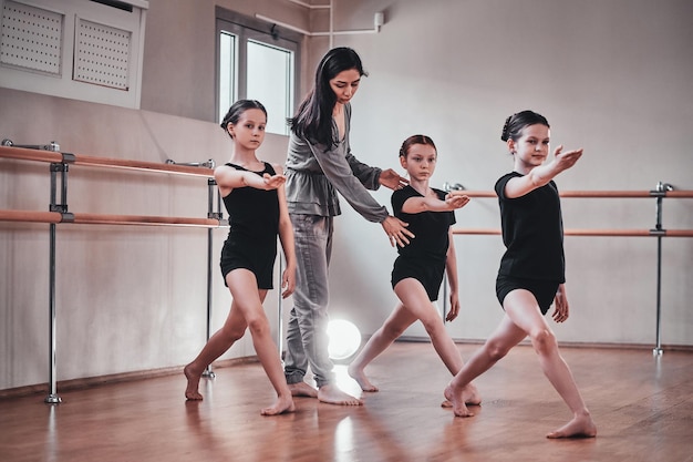 Trzy Młode, Pracowite Dziewczyny Mają Trening Baletowy Ze Swoją Atrakcyjną Nauczycielką W Jasnej Sali Treningowej.