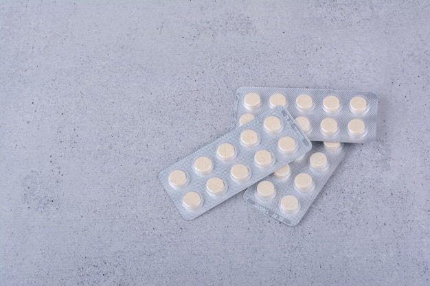 Trzy opakowania okrągłych tabletek leku na marmurowym tle. Zdjęcie wysokiej jakości