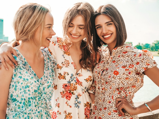 Bezpłatne zdjęcie trzy piękne uśmiechnięte dziewczyny w modnej letniej sukience pozowanie na ulicy