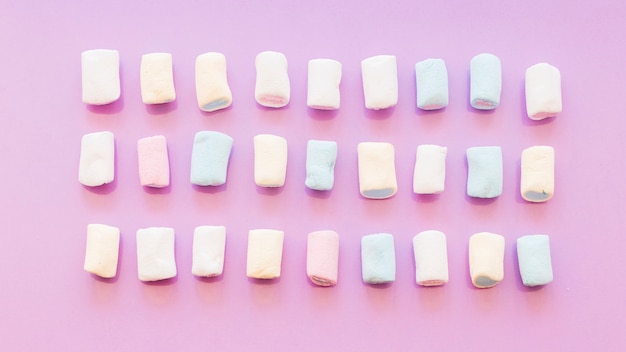 Bezpłatne zdjęcie trzy rzędu marshmallow na różowym tle