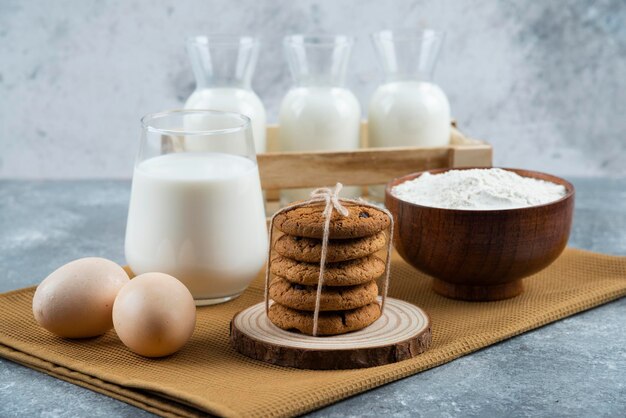 Trzy szklanki mleka z mąką i jajkami na szarym stole.