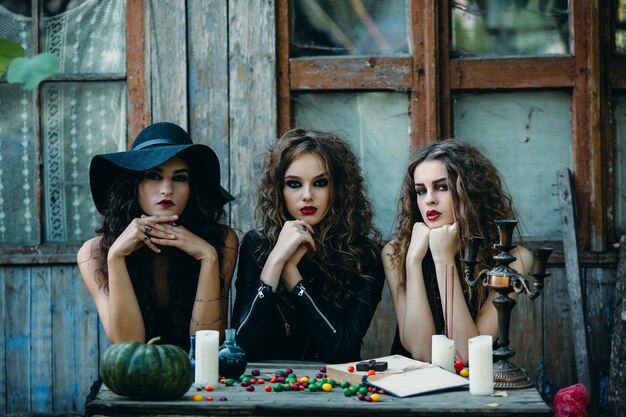 Bezpłatne zdjęcie trzy wiedźmy siedzą przy stole w przeddzień halloween