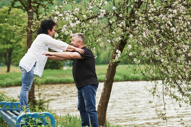 Trzymaj mnie. Wesoła para spędza miły weekend na świeżym powietrzu. Dobra wiosenna pogoda