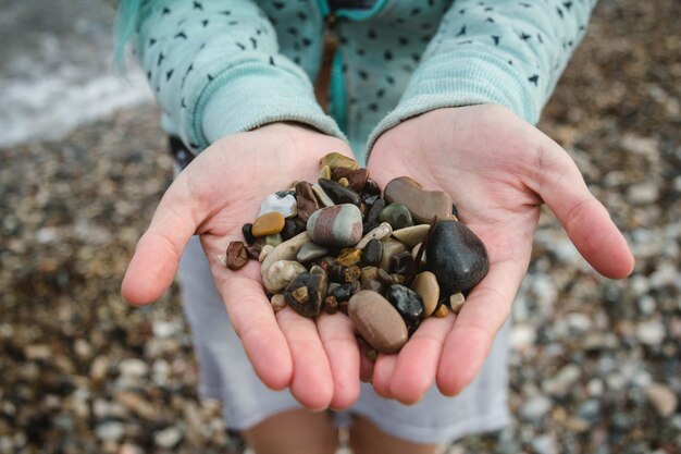 Trzymając małe kamyczki w kilku kolorach na plaży