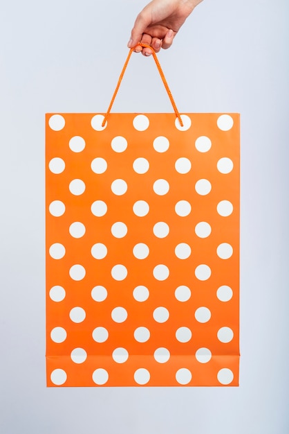 Bezpłatne zdjęcie trzymana jest pomarańczowa torba z białymi kropkami