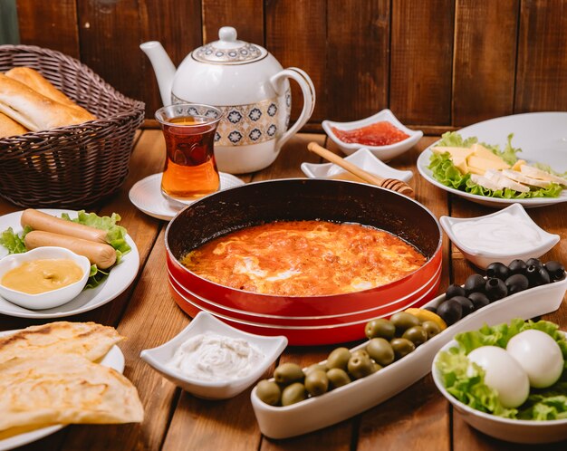 Turecki zestaw śniadaniowy z jajkiem i pomidorem, kiełbaskami, oliwkami, jajkiem, masłem i herbatą