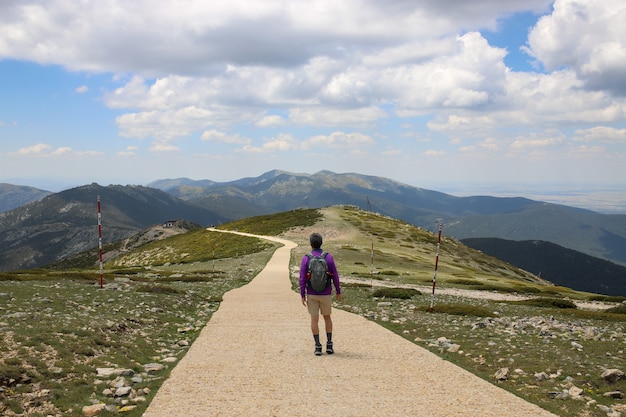 Turysta z plecakiem idący drogą po porośniętym zielenią wzgórzu - koncepcja sukcesu
