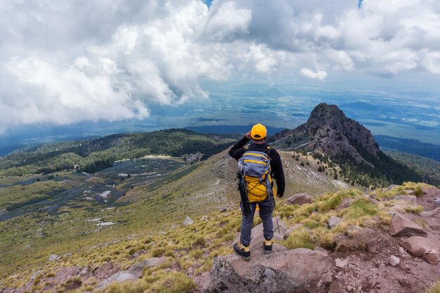 Turysta z plecakiem stojący na szczycie góry