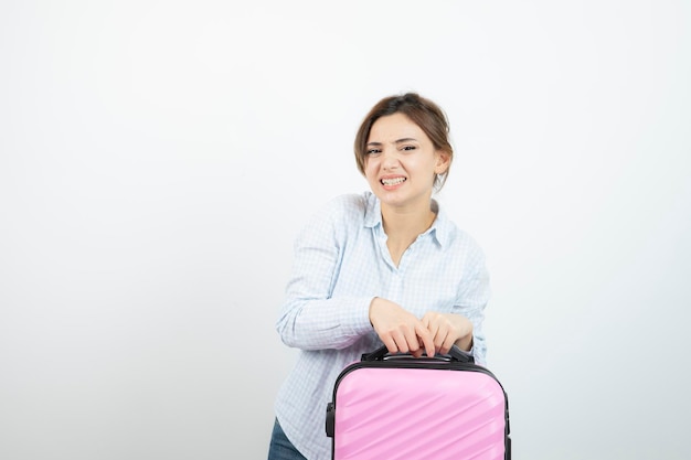 Turystyczna kobieta stojąca i trzymająca różową walizkę podróżną. Zdjęcie wysokiej jakości