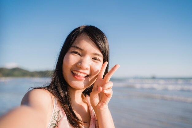 Turystyczny Azjatycki kobiety selfie na plaży, młody piękny żeński szczęśliwy ono uśmiecha się używa telefon komórkowy bierze selfie