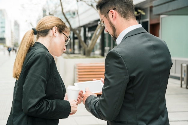 Bezpłatne zdjęcie tylni widok biznesmen i bizneswoman patrzeje mądrze telefon