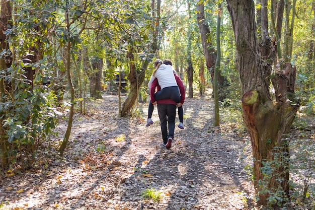 Tylny widok człowieka piggybacking swoją dziewczyną na zewnątrz