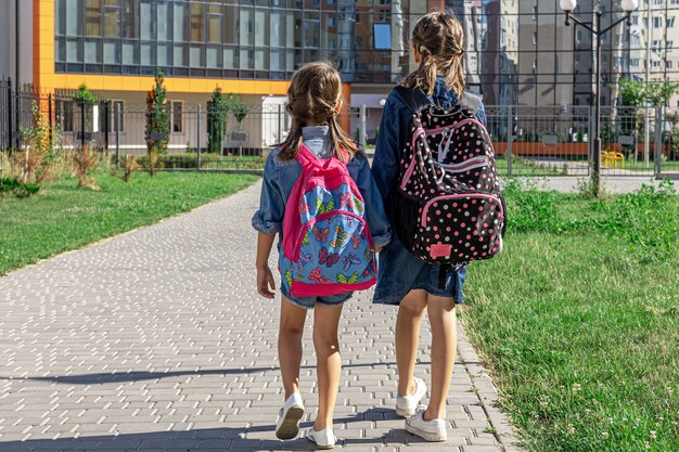 Uczennice szkoły podstawowej Dziewczyny z plecakami w pobliżu szkoły na świeżym powietrzu