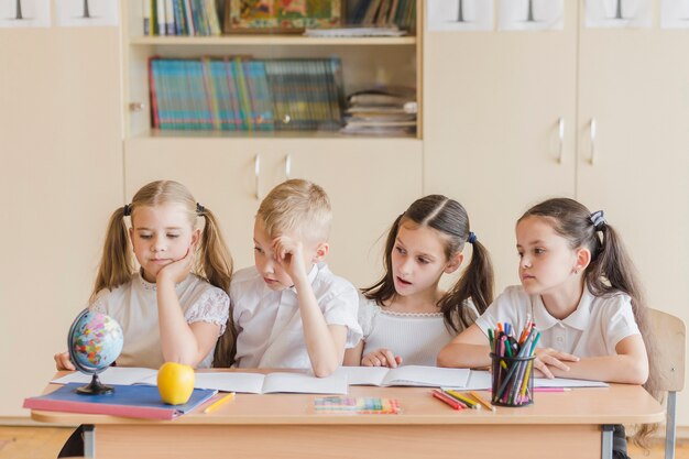 Ucznie siedzi przy szkolnym biurkiem
