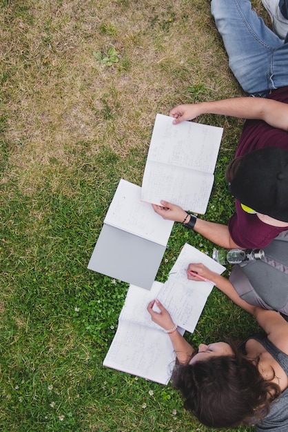 Bezpłatne zdjęcie uczniowie leżący na trawie z notebooków studiujących