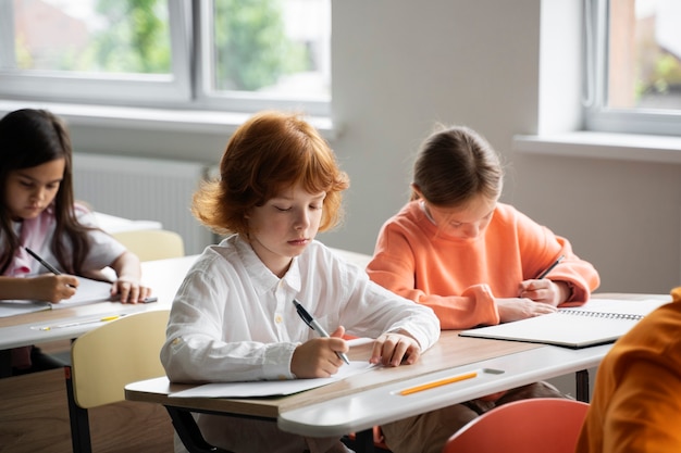 Bezpłatne zdjęcie uczniowie uczący się w szkole w swojej klasie