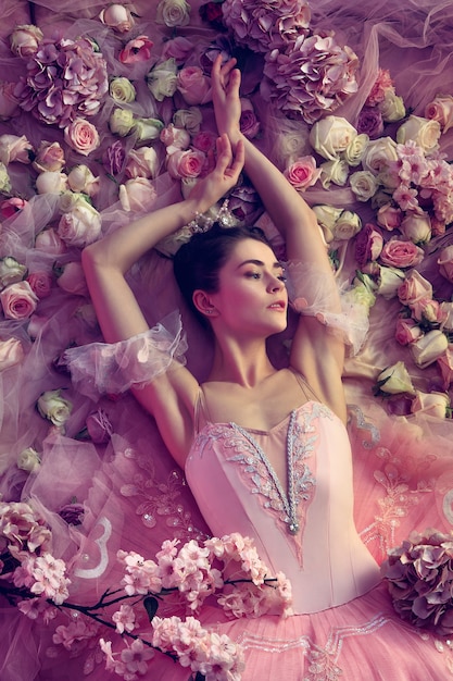 Uczuciowość. Widok z góry piękna młoda kobieta w różowej spódniczce baletowej otoczonej kwiatami. Wiosenny nastrój i delikatność w koralowym świetle. Koncepcja wiosny, kwitnienia i przebudzenia przyrody.