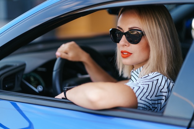 Ufna I Piękna Kobieta W Okularach Przeciwsłonecznych. Widok Z Tyłu Atrakcyjnej Młodej Kobiety W Codziennym Noszeniu Prowadzenia Samochodu
