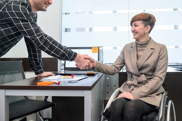 Bezpłatne zdjęcie ufny bizneswoman w wózek inwalidzki trząść ręki