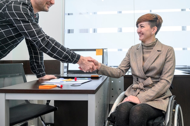 Ufny bizneswoman w wózek inwalidzki trząść ręki