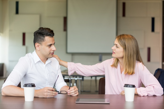 Ufny bizneswomanu klapania męski kolega na ramieniu przy kawową przerwą.